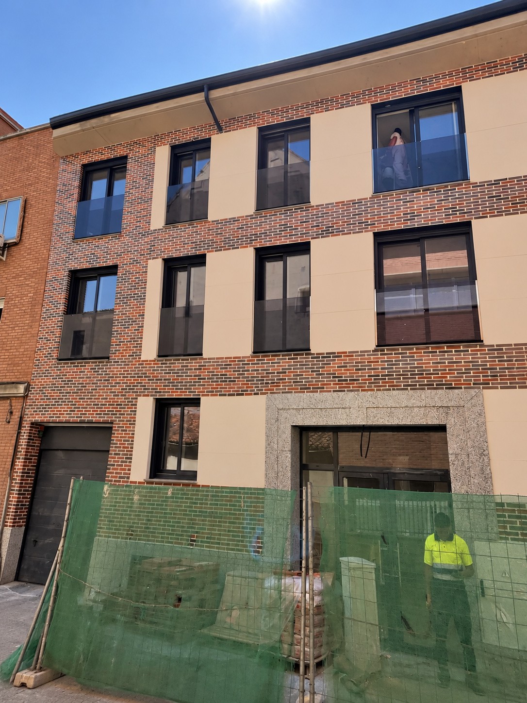Fachada del edificio residencial de Alcalá de Henares durante la obra, con el portal y el cerramiento provisional visibles